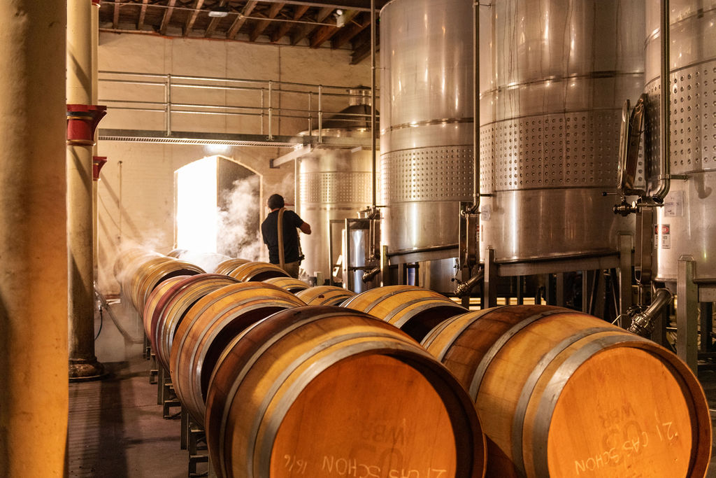 A man inside the winery surrounded by tanks and barrels